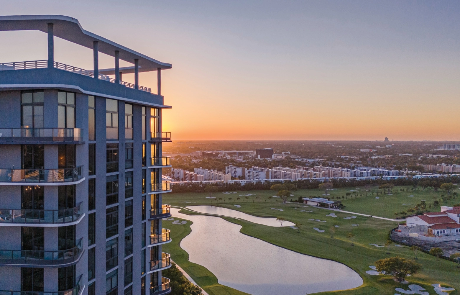 Aerial view of exterior of the Mondrian Hallandale Beach Residences in South Florida with a golf course in the background.